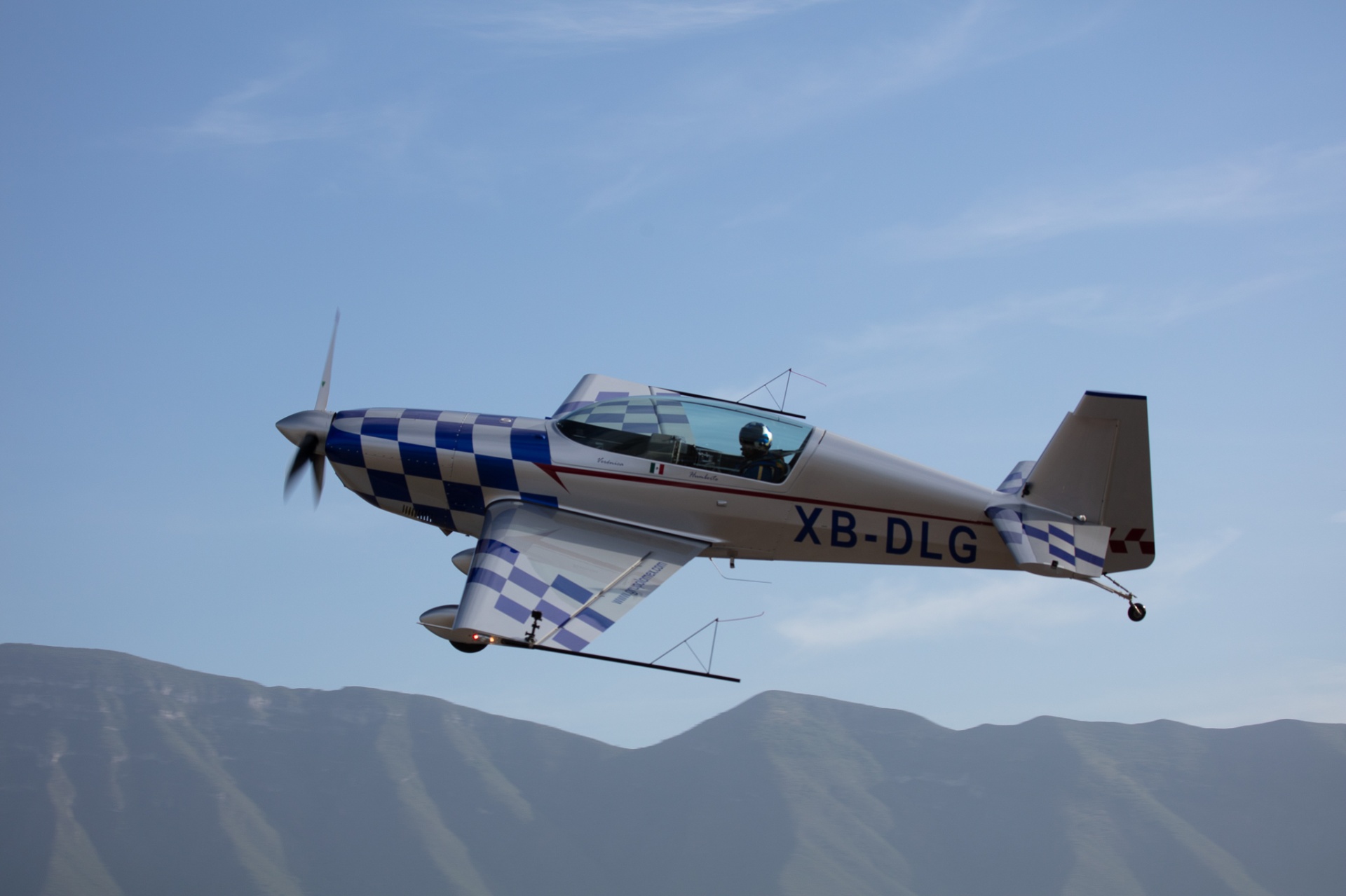 Profile of XB-DLG aerobatic plane banking in front of mountain range