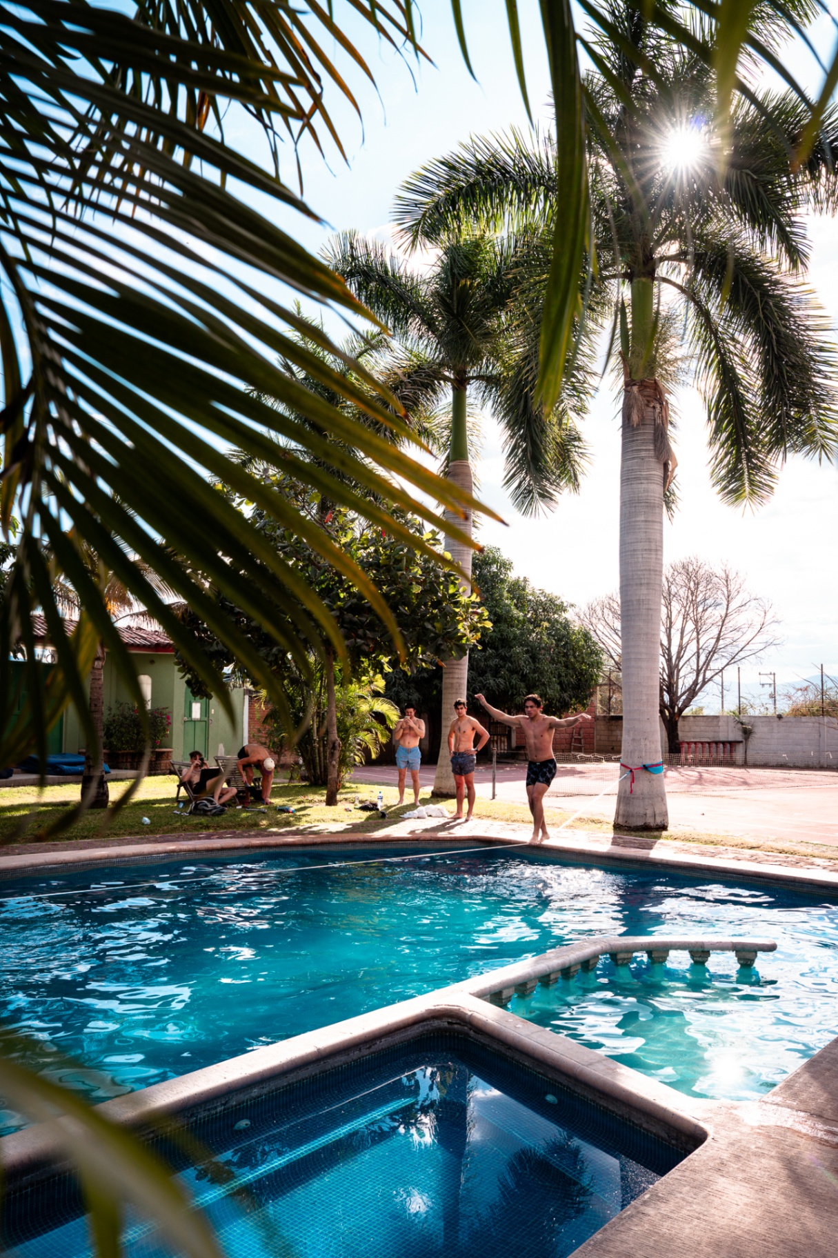 Crew hanging by a pool under tall palms between shoots in Mexico