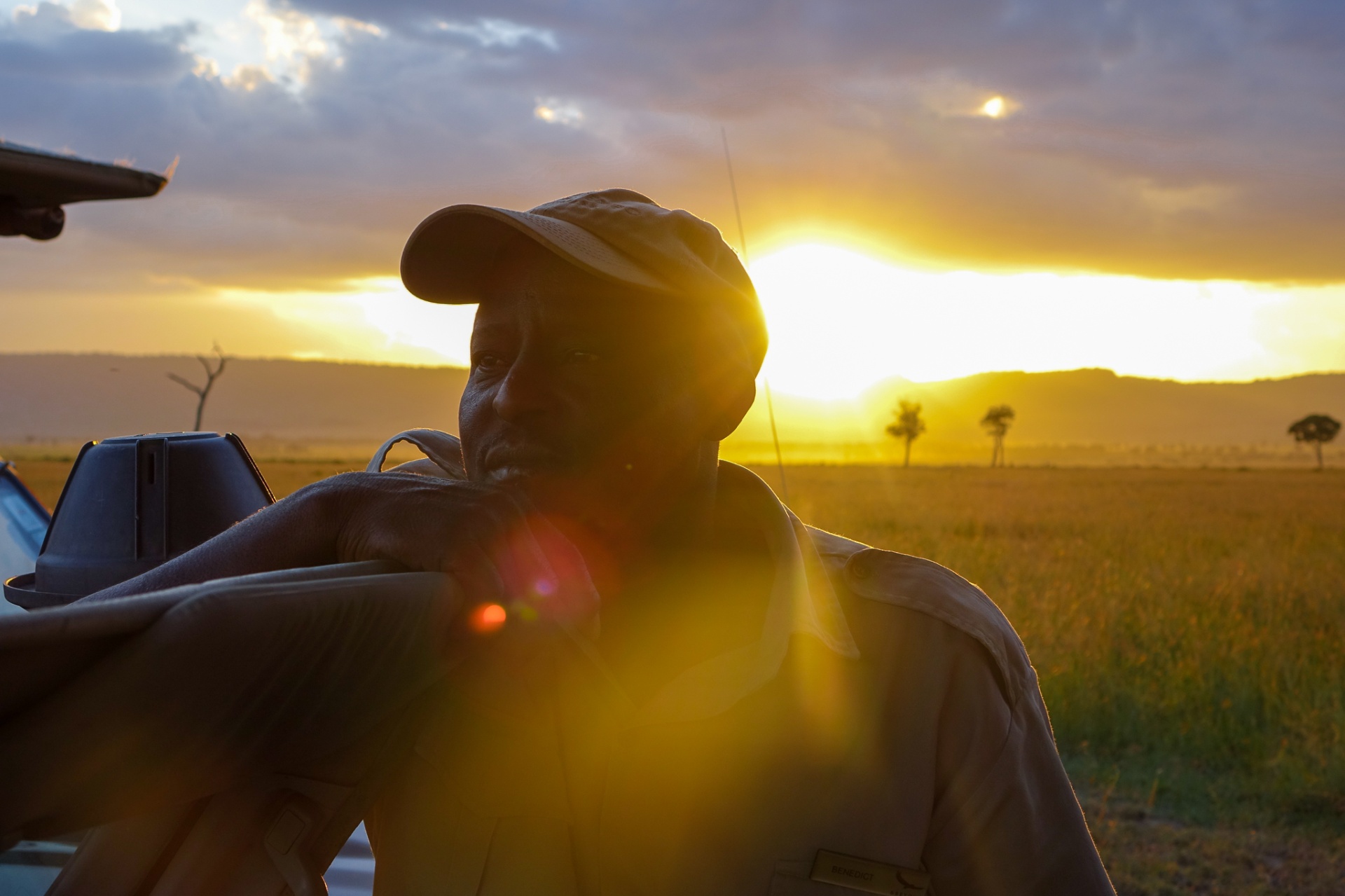 Silhouette of a safari guide leaning on a 4x4 against a Serengeti sunset