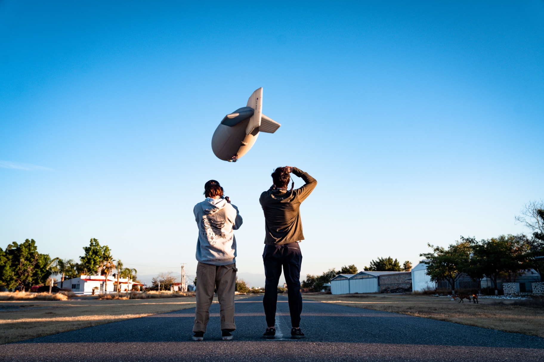 Two operators launching a small cinema airship straight up into a clear sky