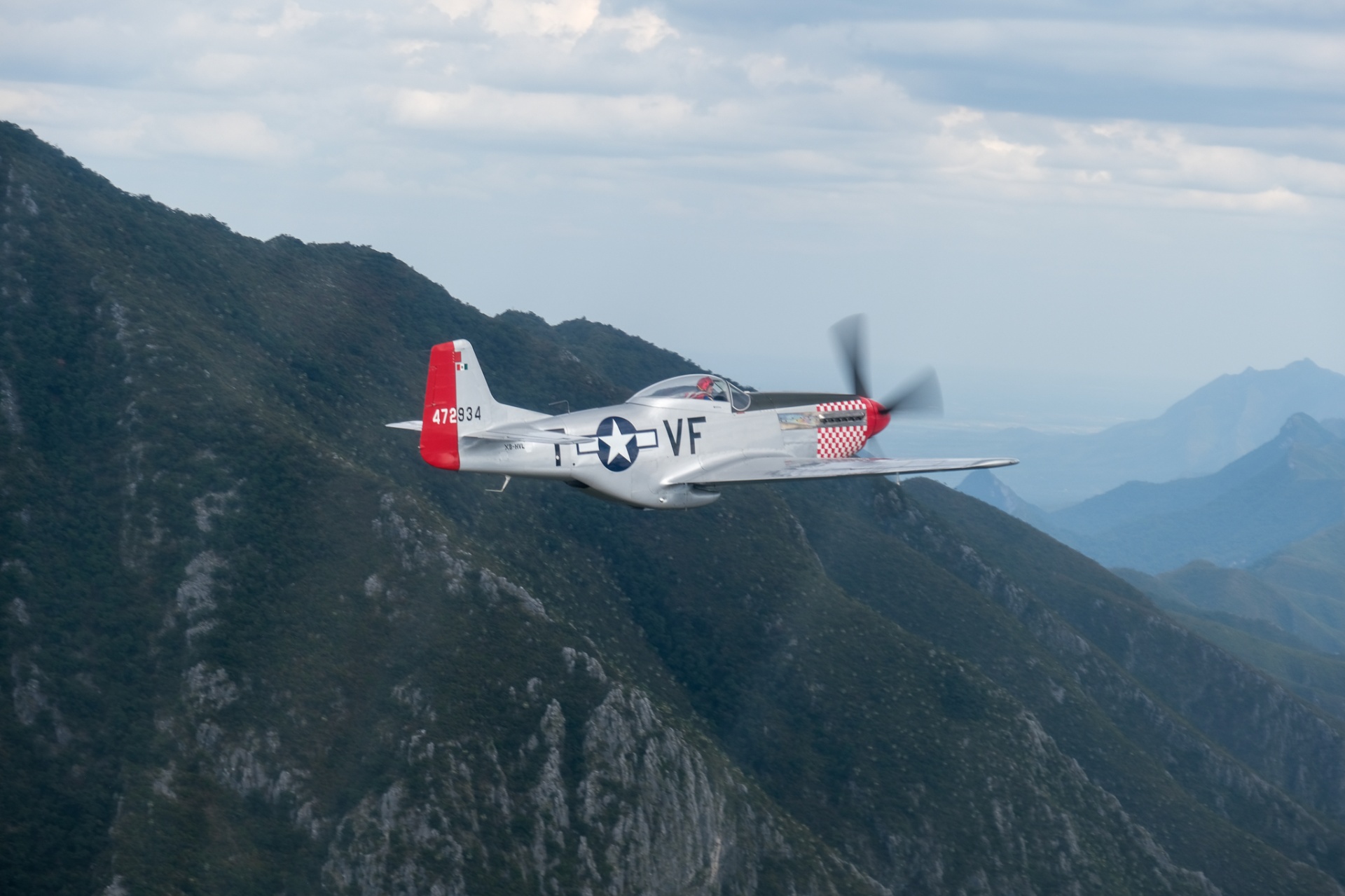 Silver P-51 Mustang hugging a ridgeline in the Sierra Madre