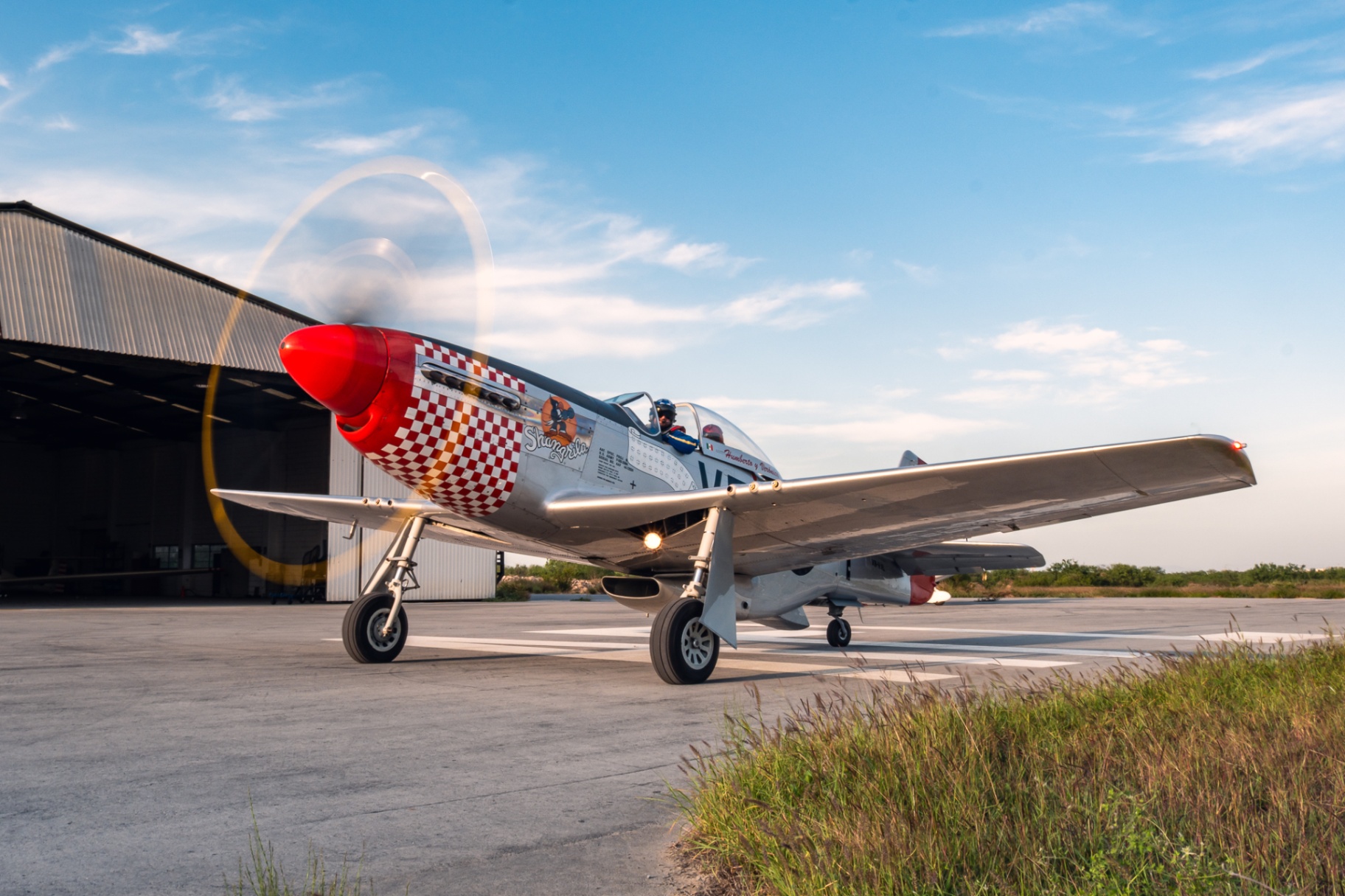 P-51 Mustang Shangri-La taxiing out of hangar with prop disk catching the sun