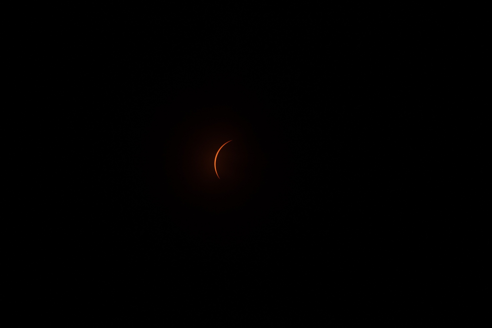 Final crescent of the sun glowing orange against a black sky during total eclipse