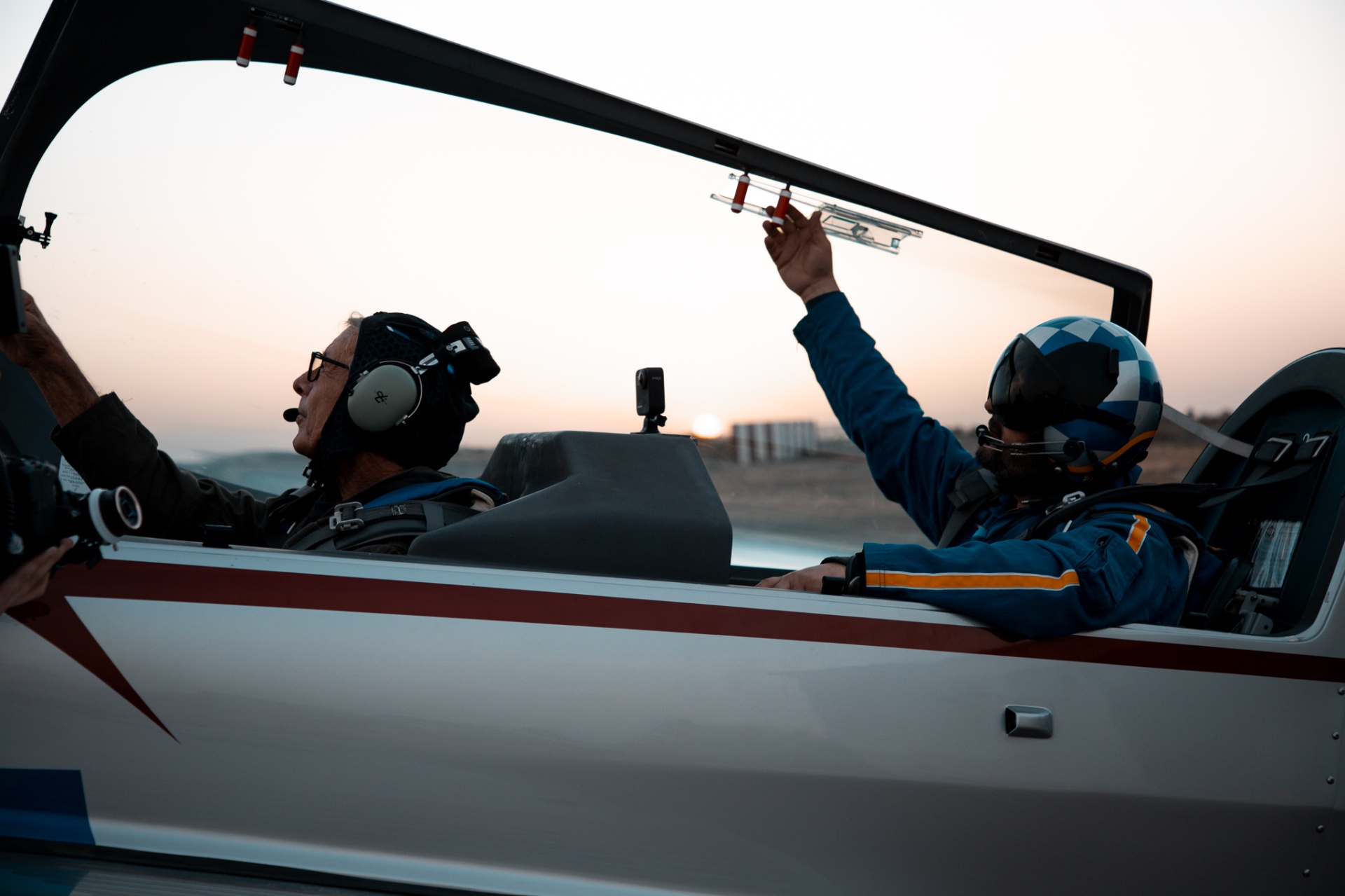 Pilot and passenger seated in Extra cockpit as canopy closes at sunset